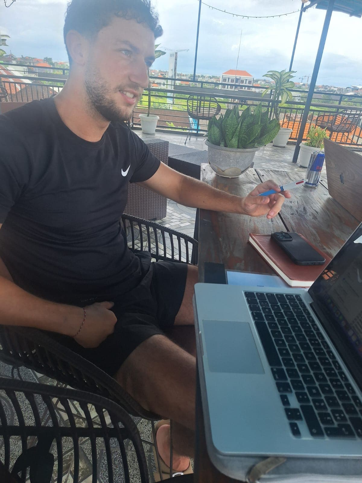 Homme travaillant sur un ordinateur portable sur une terrasse de toit surplombant la ville.