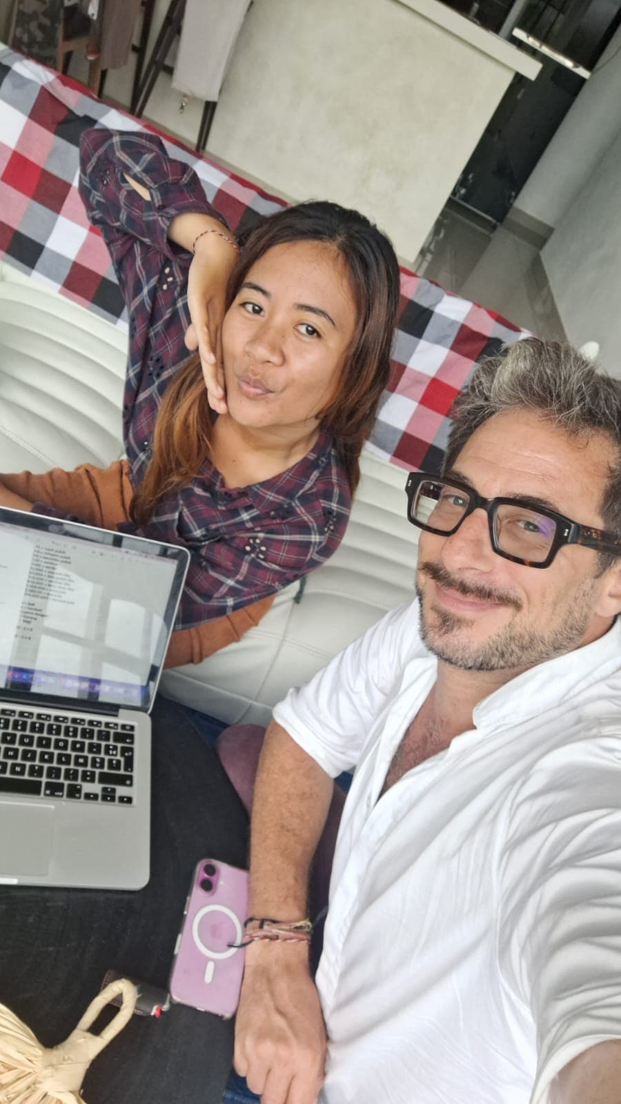 Homme à lunettes et femme en chemise à carreaux posant devant un ordinateur portable ouvert.