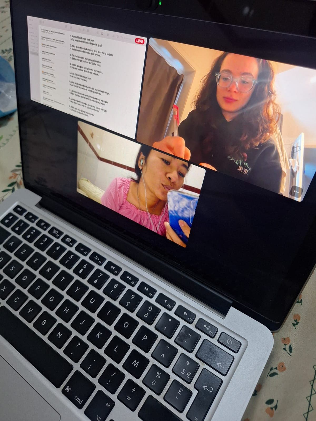 Appel vidéo sur ordinateur portable entre deux femmes étudiant un document de traduction linguistique.